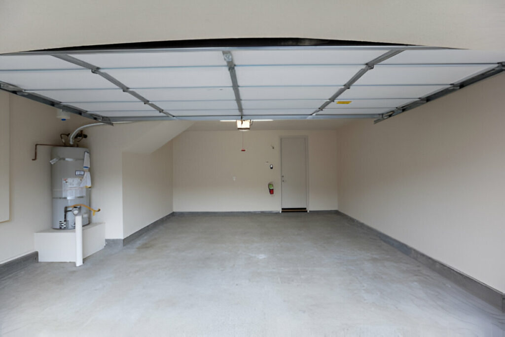 Empty residential garage with open door and air conditioner on the left side.