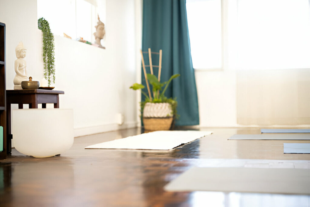 Peaceful home yoga and meditation room with yoga mats, a Buddha statue, and natural light