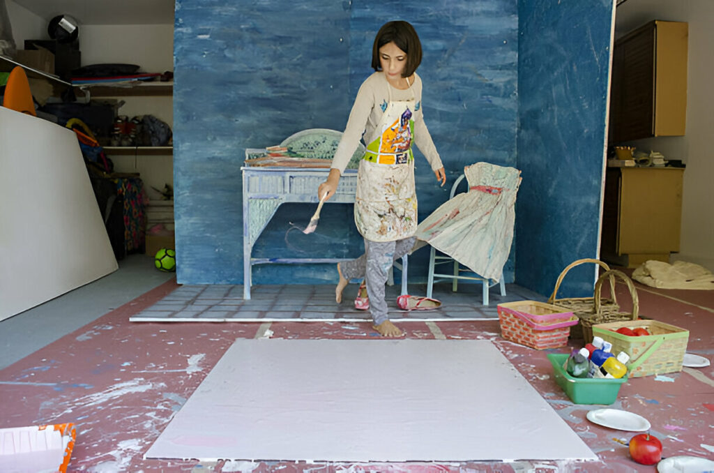 Young artist painting in a creative home studio space with colorful supplies and painted furniture