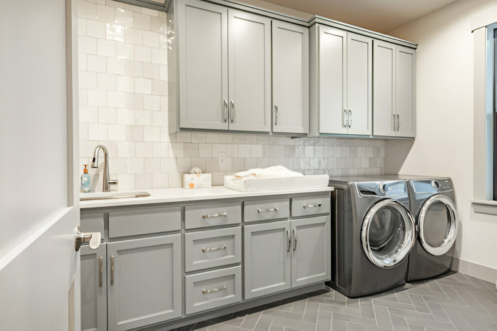 Modern laundry room with gray cabinets, a countertop with a built-in sink, and a matching washer and dryer set