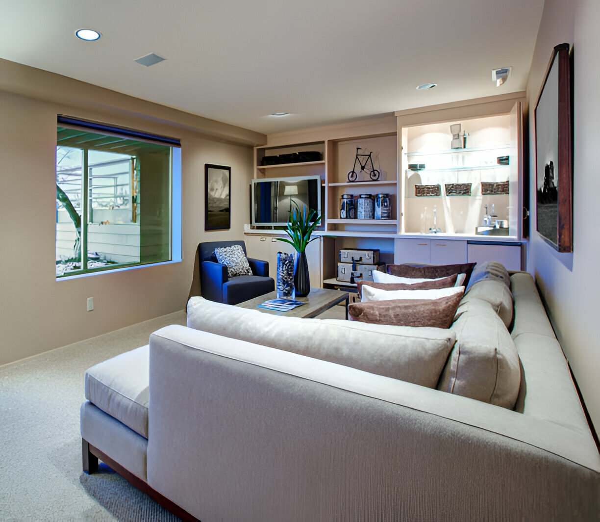 Modern basement living room with a sectional sofa, built-in shelves, and a small bar area