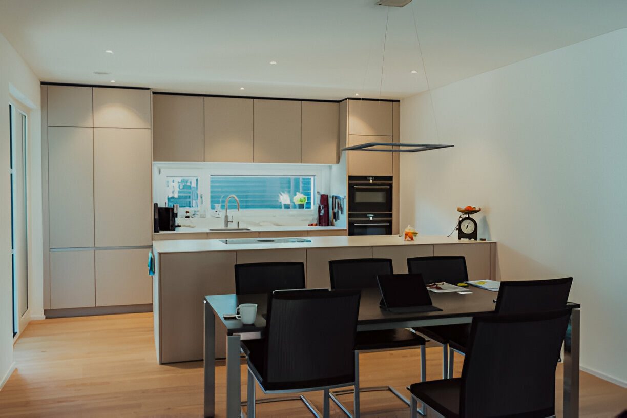 Minimalist kitchen and dining space with black chairs and built-in appliances
