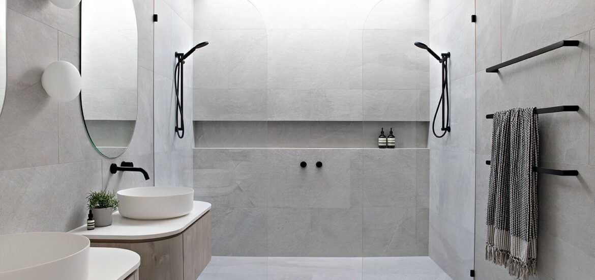 Modern Scandinavian bathroom featuring double walk-in showers, floating vanities, round mirrors, and matte black fixtures