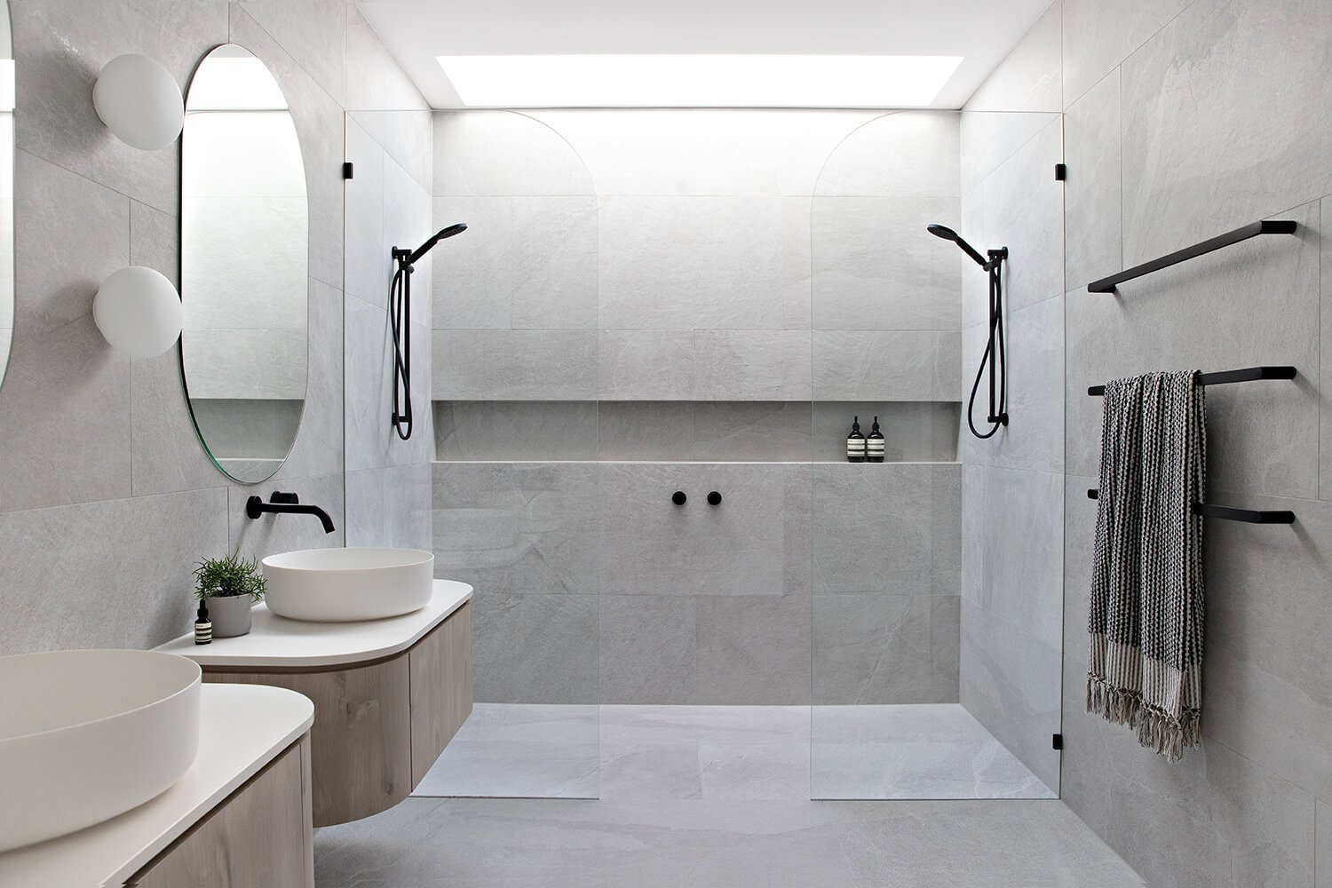 Smart Remodeling Solutions for Small Bathrooms 6 Modern Scandinavian bathroom featuring double walk-in showers, floating vanities, round mirrors, and matte black fixtures