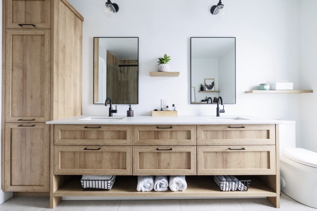 Custom Cabinetry Trends for Bathrooms to Watch in 2025 6 Contemporary bathroom with wooden double-sink vanity, black faucets, two mirrors, and minimalist shelving