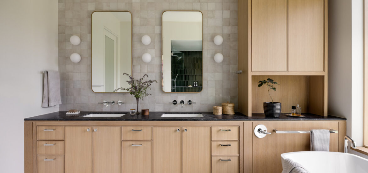 Bathroom featuring light wood cabinetry, black countertops, dual rectangular mirrors, and soft tile backsplash