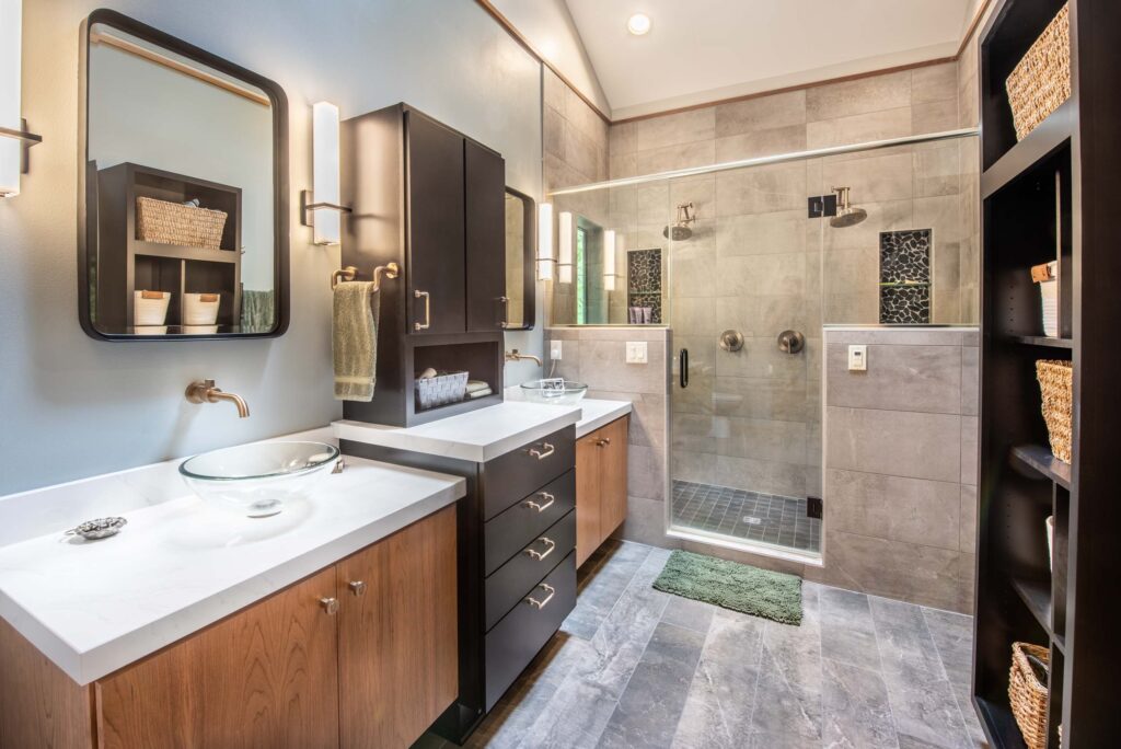Custom Cabinetry Trends for Bathrooms to Watch in 2025 12 Modern bathroom featuring double vanities with vessel sinks, a large glass walk-in shower, and wood-accented cabinetry