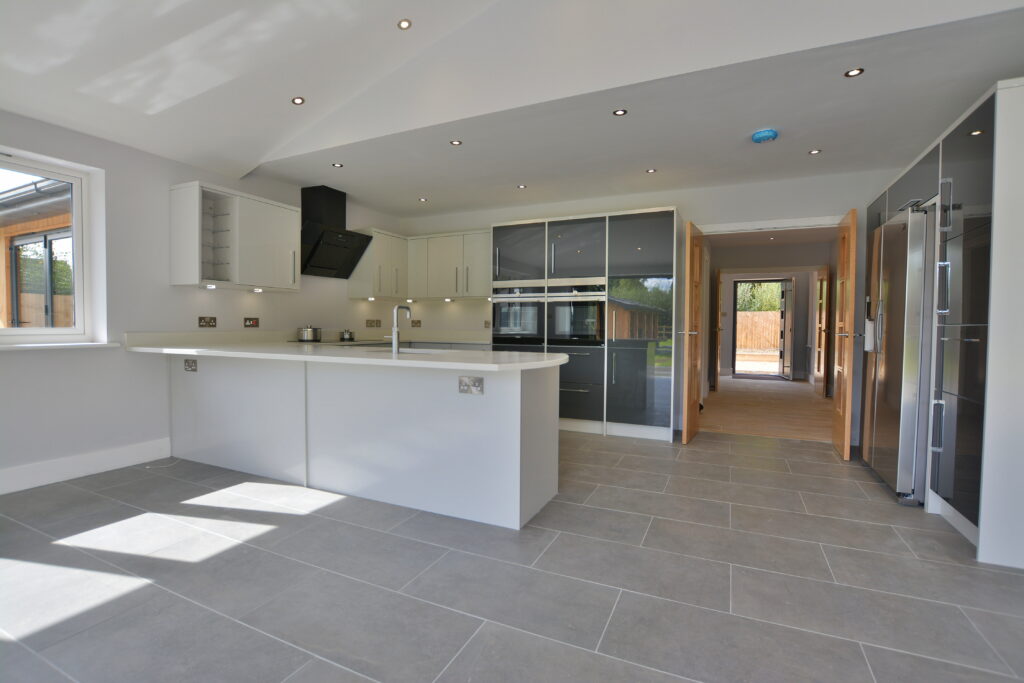 Best Kitchen Flooring Options 12 Contemporary kitchen featuring large grey ceramic floor tiles, sleek white island, built-in appliances, and glossy cabinets