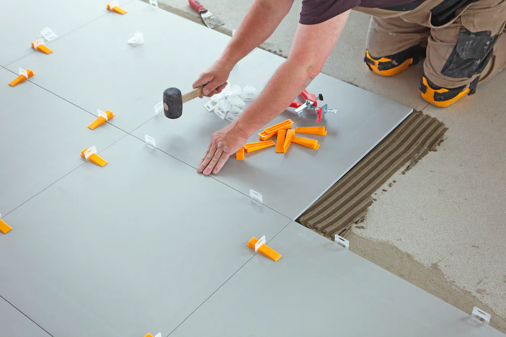 The Ultimate Guide to Kitchen and Floor Tiles 13 Contractor installing large floor tiles using tile leveling clips and mortar for even surface alignment