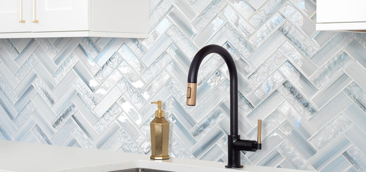 Contemporary white kitchen with blue glass herringbone backsplash, black matte faucet, and quartz countertop