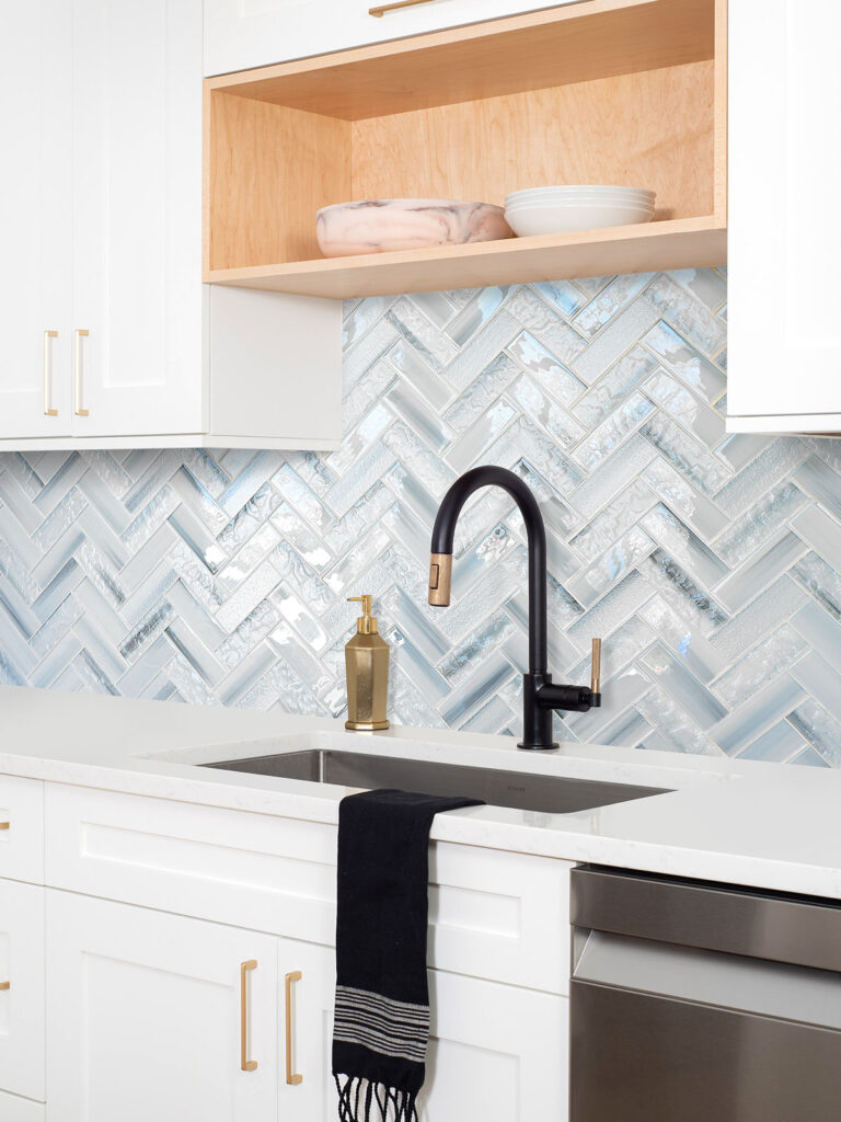 Modern Kitchen Backsplash Ideas in Alide, VA 7 Contemporary white kitchen with blue glass herringbone backsplash, black matte faucet, and quartz countertop