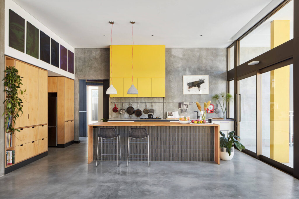 Best Kitchen Flooring Options 14 Contemporary kitchen with concrete floors, yellow upper cabinets, wood accents, and large glass doors