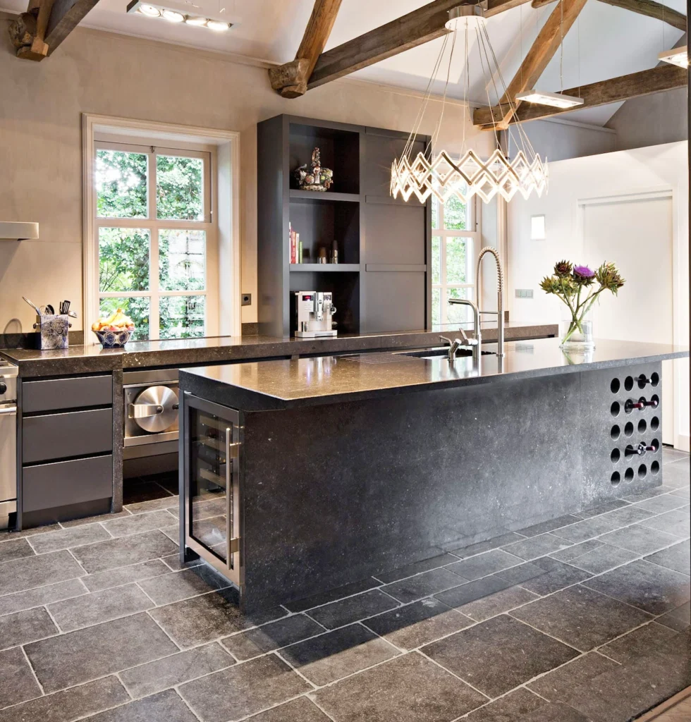 Best Kitchen Flooring Options 11 Rustic modern kitchen featuring natural stone tile flooring, exposed wooden beams, and a sleek black island with wine storage