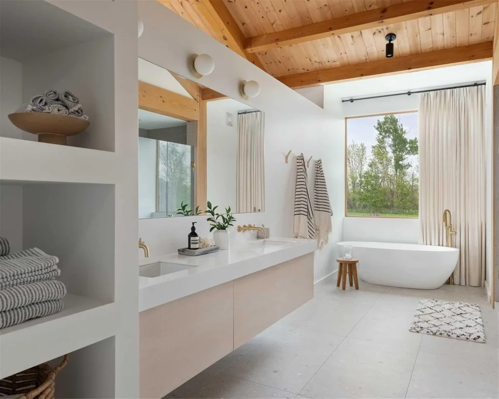 Custom Cabinetry Trends for Bathrooms to Watch in 2025 13 Bright Scandinavian-style bathroom with floating double vanity, gold fixtures, a freestanding tub, and natural wood ceiling