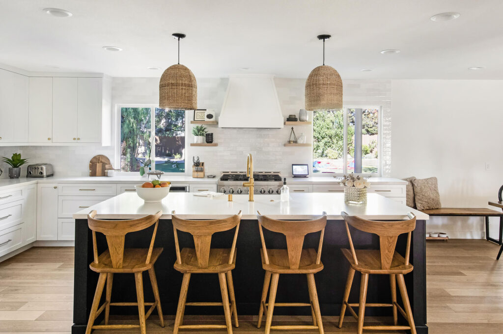 Contemporary kitchen with black and gold island, wicker pendant lights, and wooden bar stools