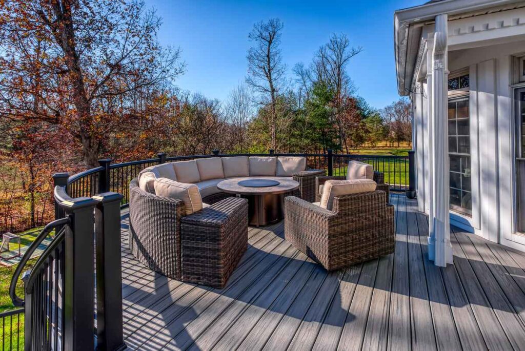 Elevated outdoor deck with curved wicker seating and fire pit table