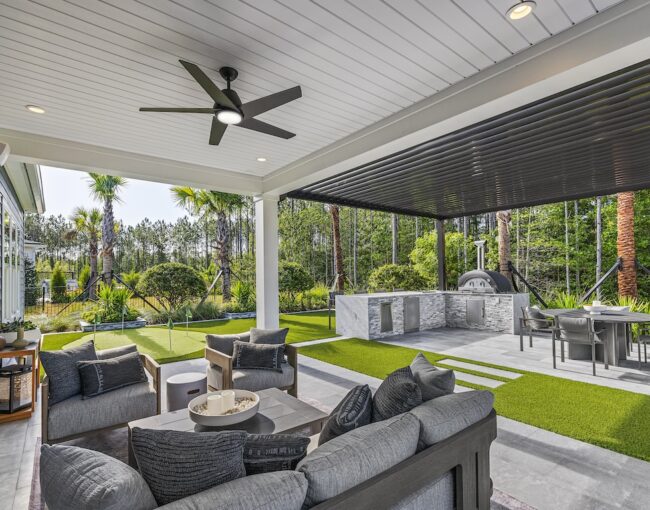 Modern covered patio with outdoor kitchen, lounge seating, and putting green