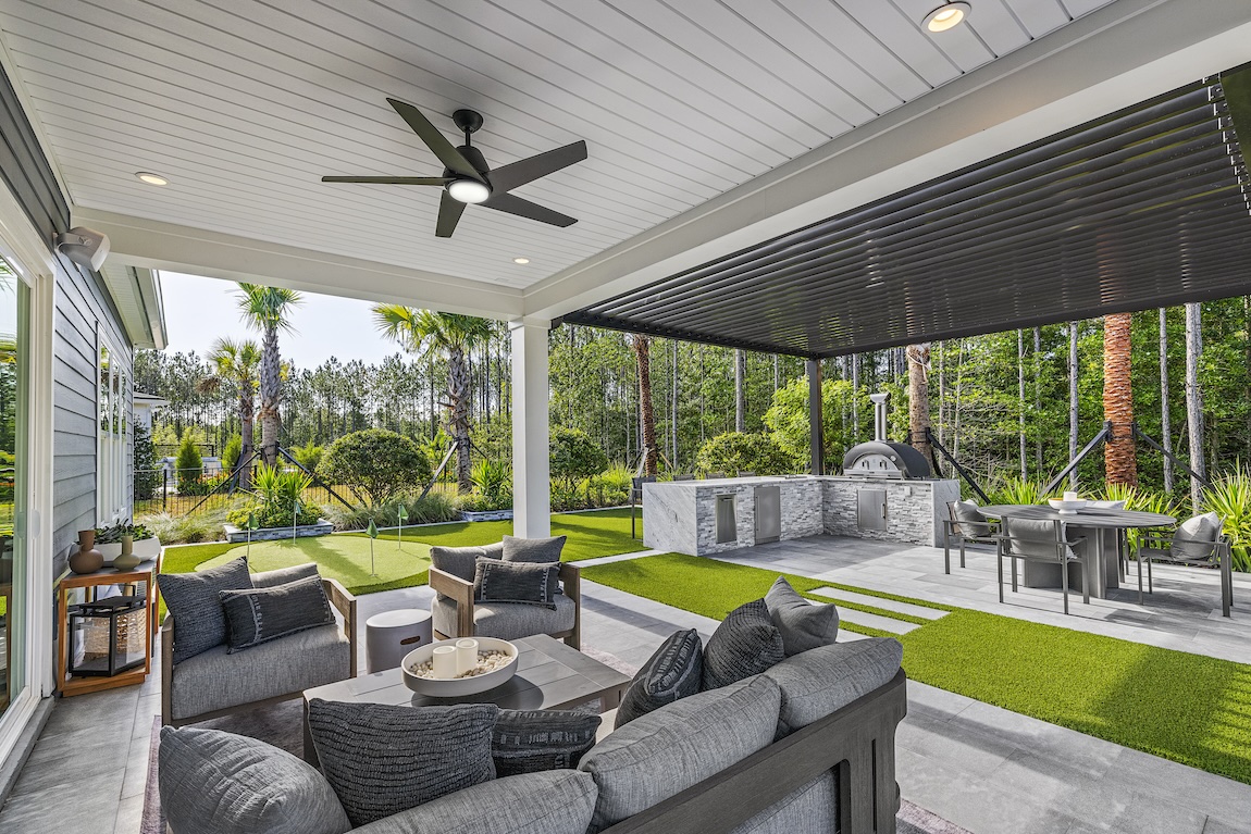 Modern covered patio with outdoor kitchen, lounge seating, and putting green