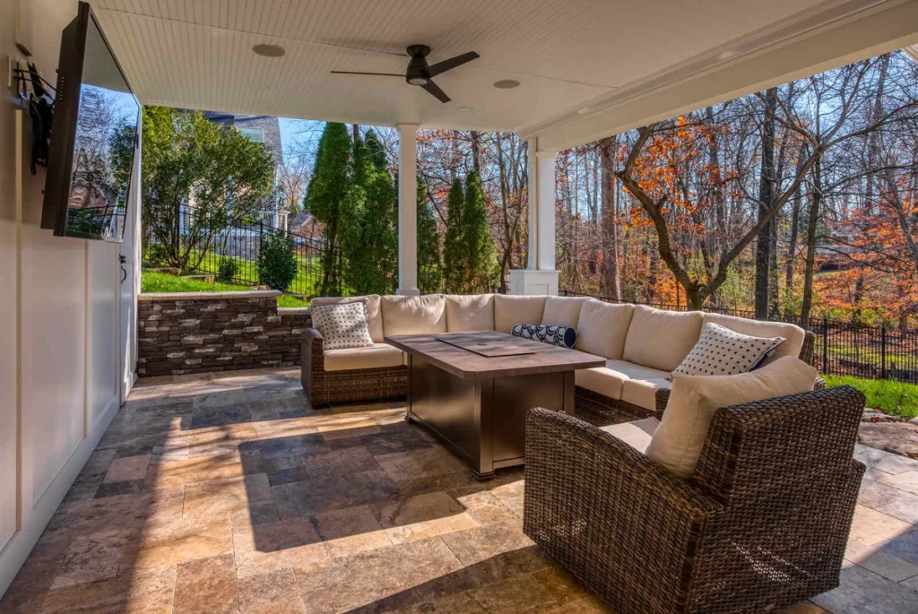 Covered outdoor patio with sectional sofa, tile flooring, and wall-mounted TV