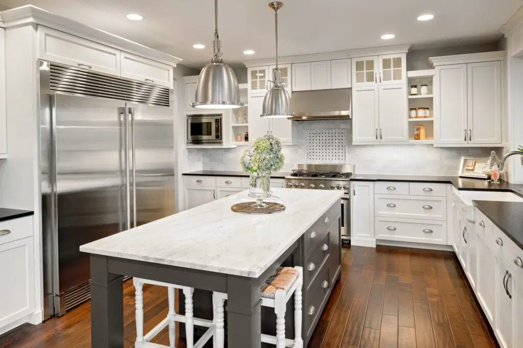 Spacious kitchen featuring white cabinetry, stainless steel appliances, marble island countertop, and dark hardwood flooring