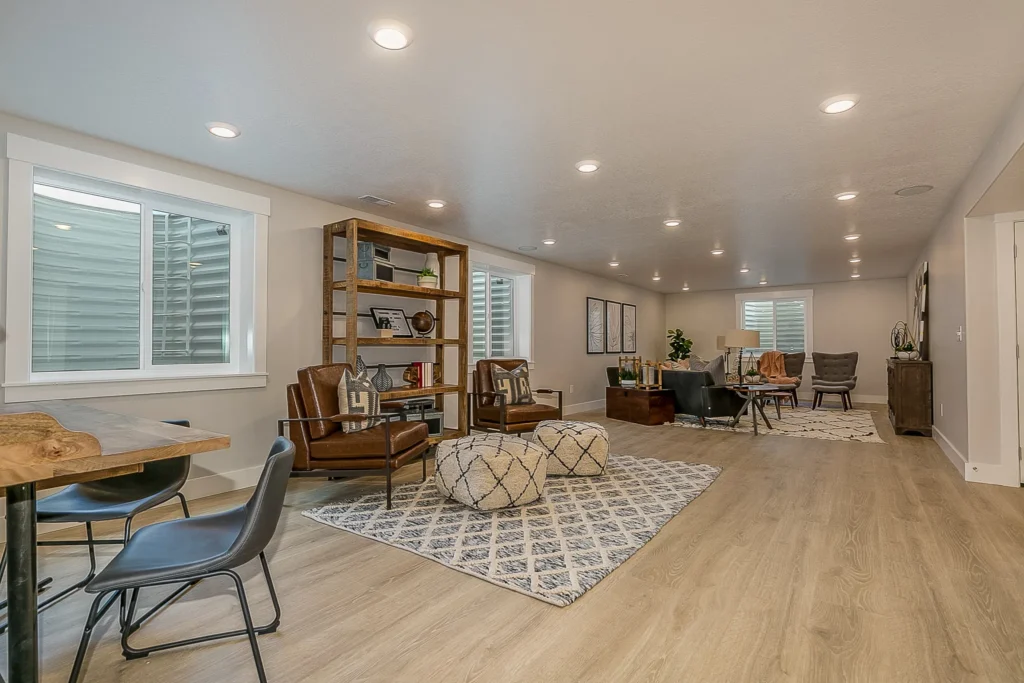 Spacious finished basement featuring wood laminate floors, rugs, multiple seating areas, bookshelves, and modern decor