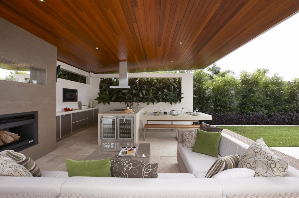 Luxurious outdoor kitchen and lounge area with wooden ceiling and modern furniture
