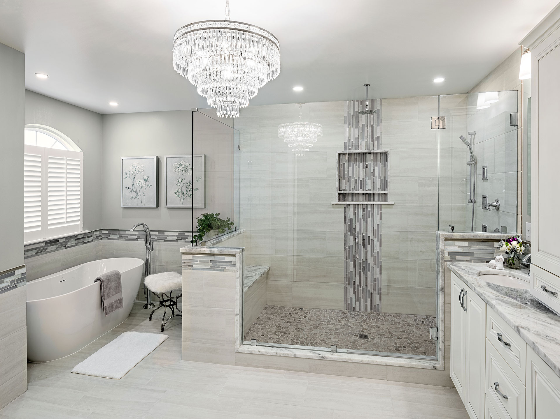 Luxurious bathroom with a freestanding bathtub, large glass-enclosed shower, and elegant chandelier.