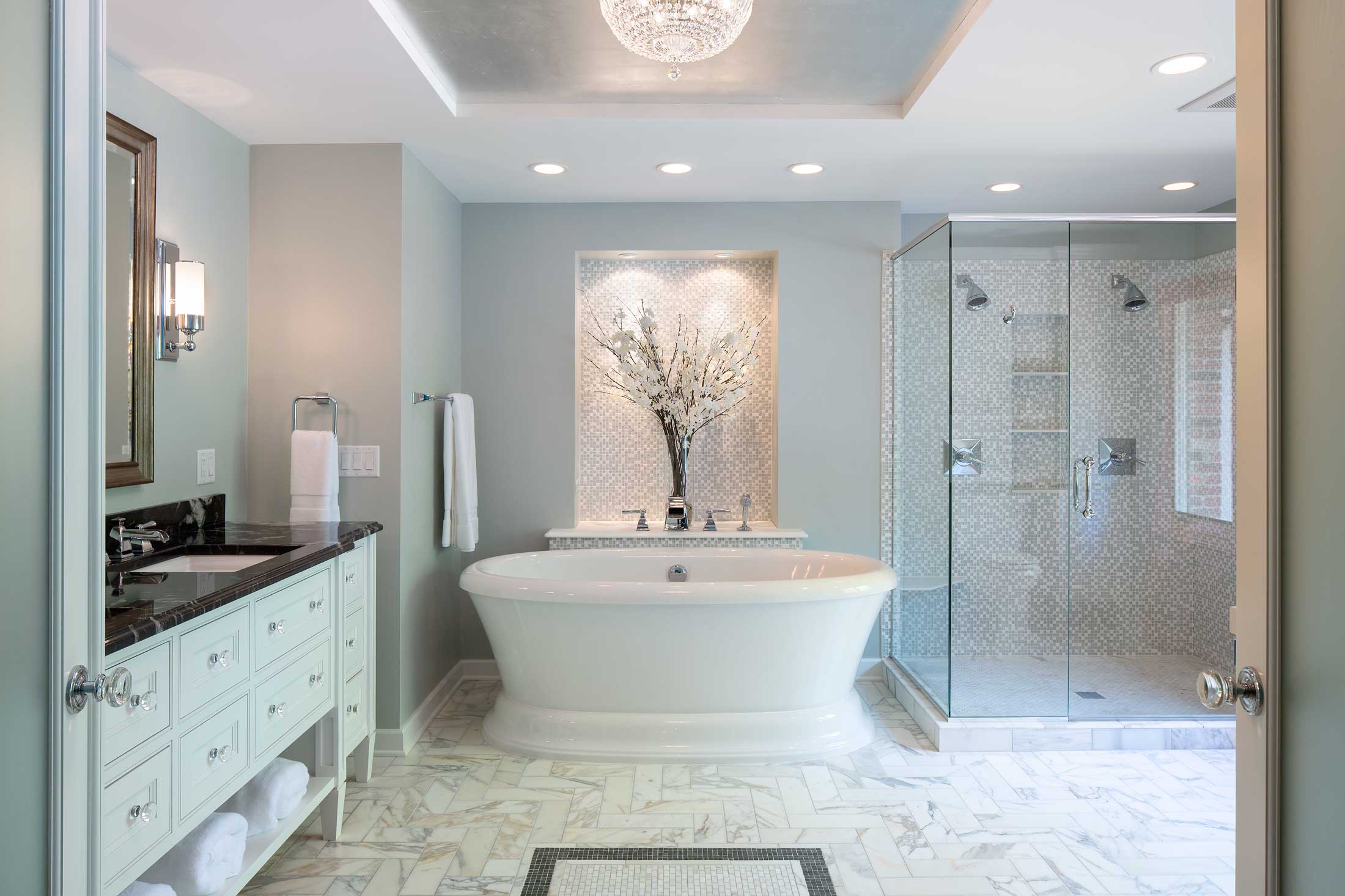 Luxurious bathroom with freestanding tub, marble flooring, and glass-enclosed shower.