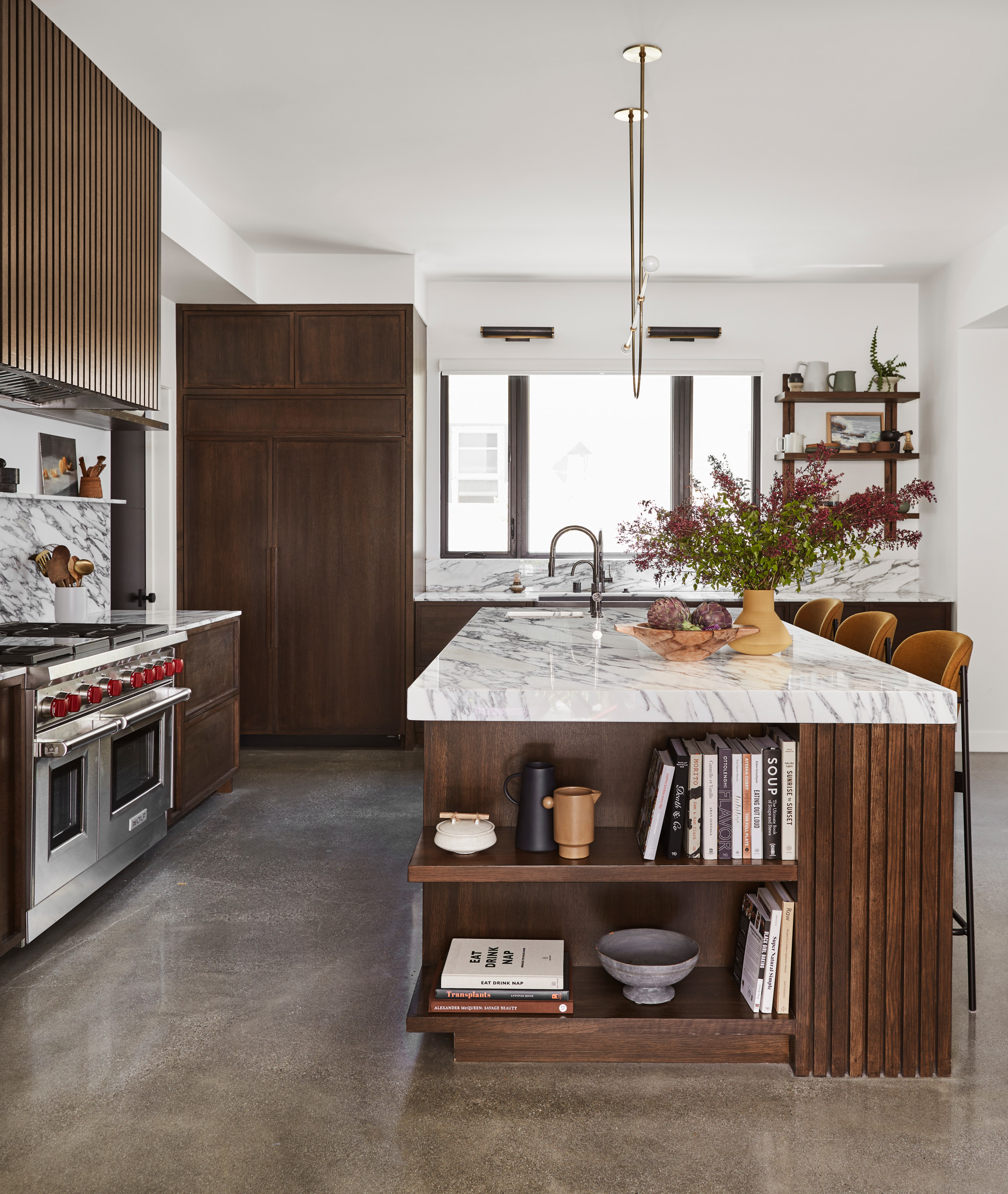 Luxury kitchen with marble countertops, dark wood cabinetry, and built-in island shelving.