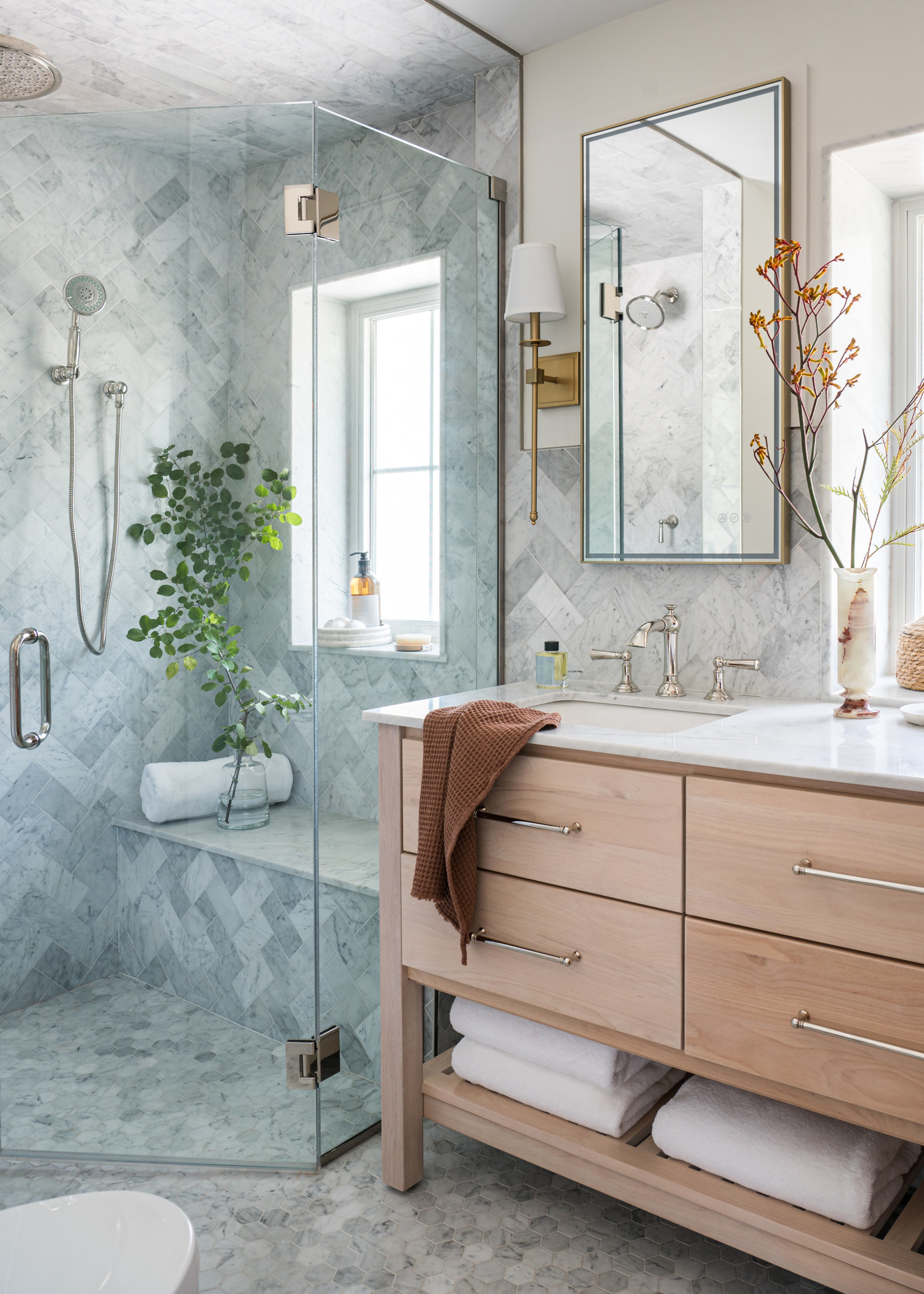 Light wood vanity bathroom with marble tile shower and glass enclosure.