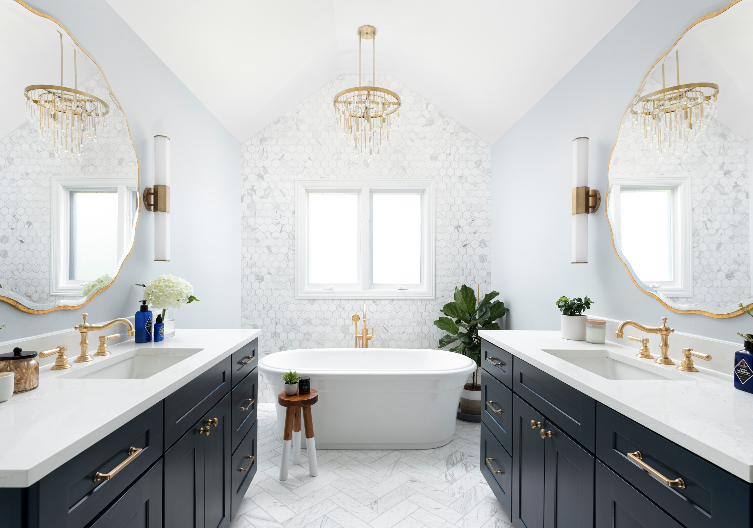 Luxury bathroom with navy double vanities, freestanding bathtub, and gold accents.