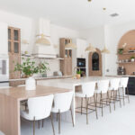 Spacious modern kitchen with wood accents, white cabinetry, and large island seating.