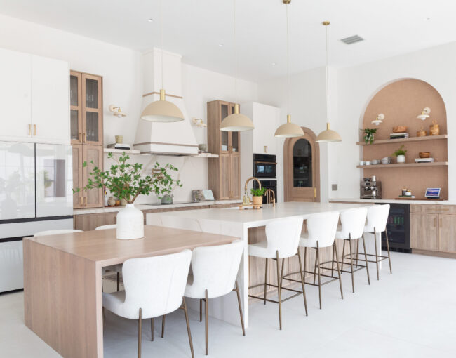 Spacious modern kitchen with wood accents, white cabinetry, and large island seating.