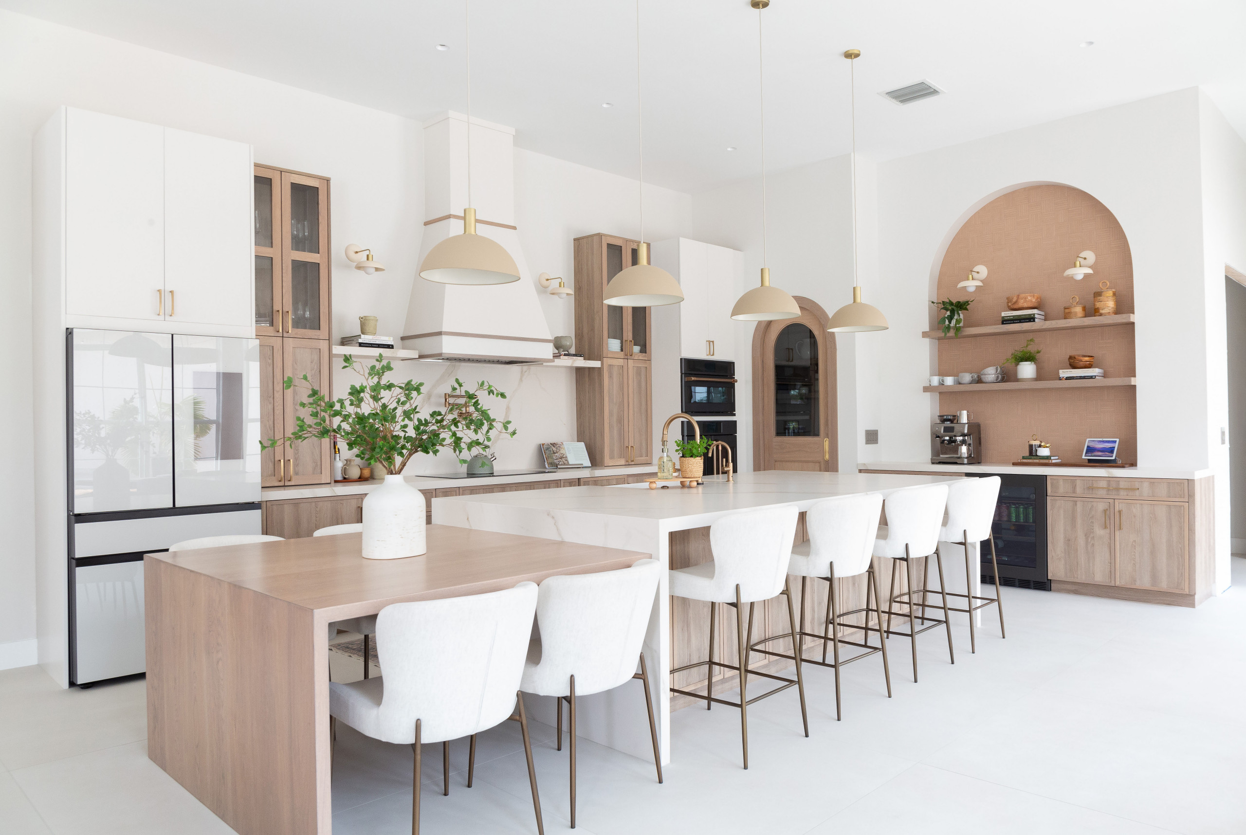 Spacious modern kitchen with wood accents, white cabinetry, and large island seating.