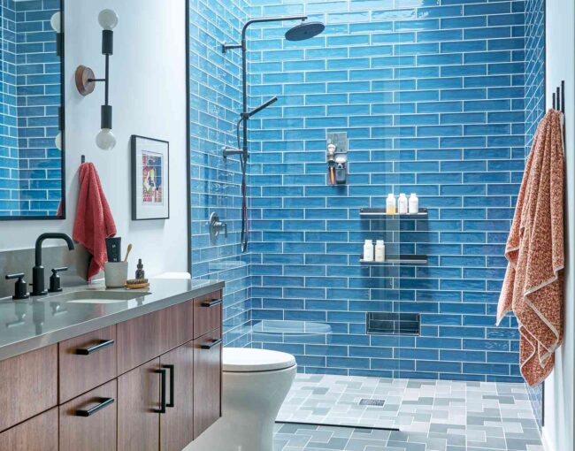 Modern bathroom with blue subway tile shower and floating wood vanity.