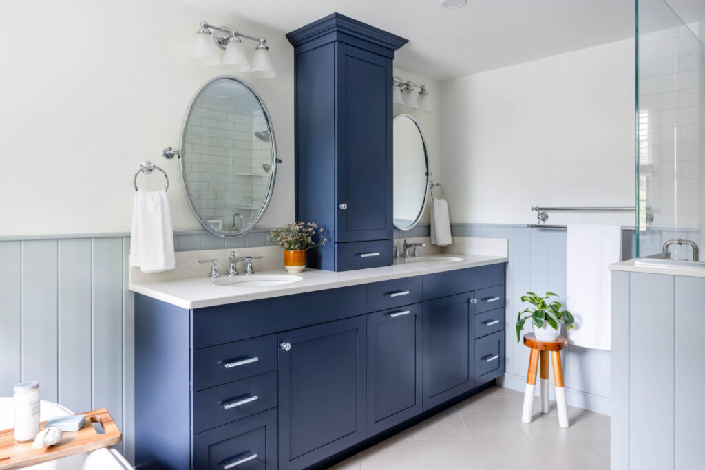 Modern bathroom with navy blue vanity, double sinks, and round mirrors