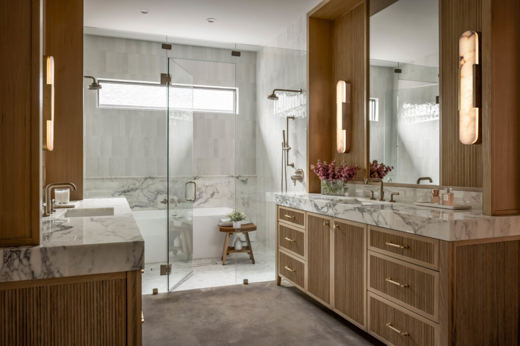 Luxurious bathroom with marble countertops, wood cabinetry, and glass-enclosed shower