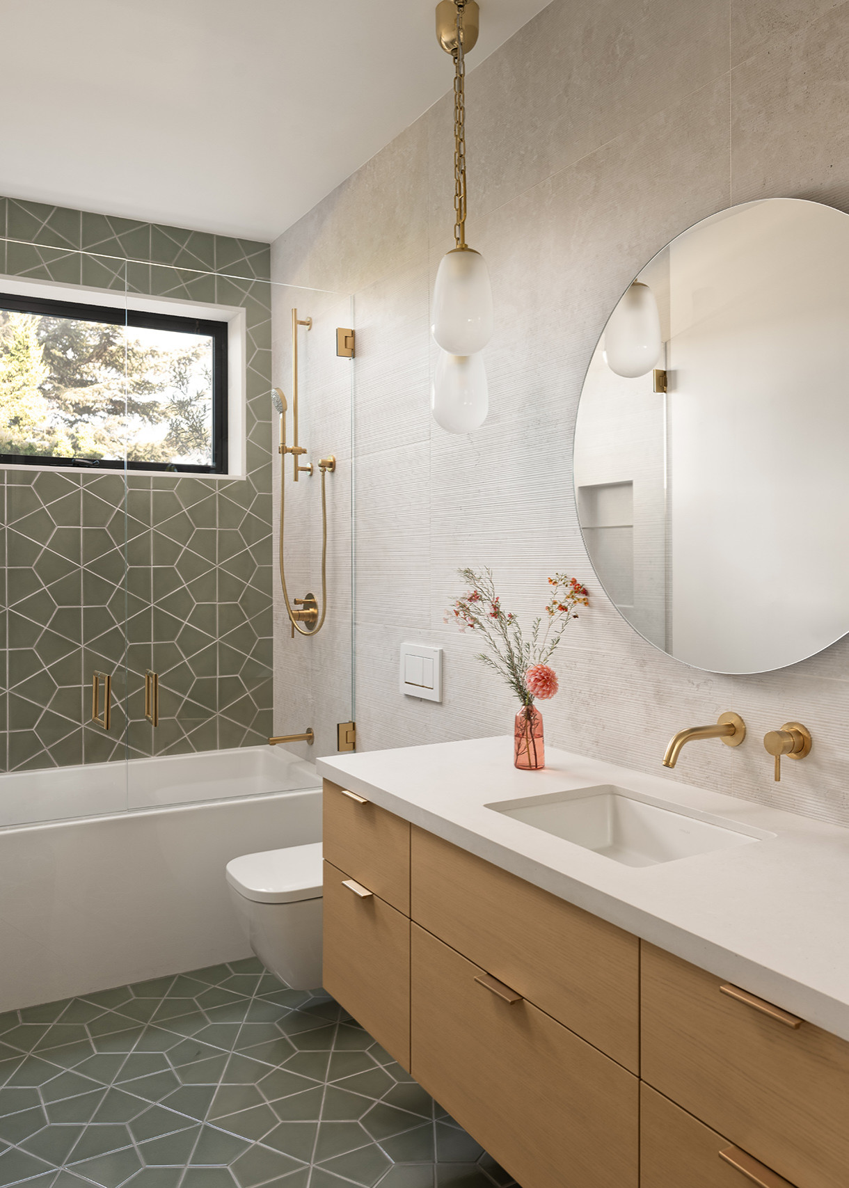 Modern bathroom with geometric green tile accents, floating wooden vanity, and gold fixtures.