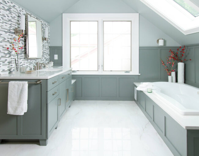 Elegant bathroom with green cabinetry, built-in bathtub, and mosaic tile backsplash.