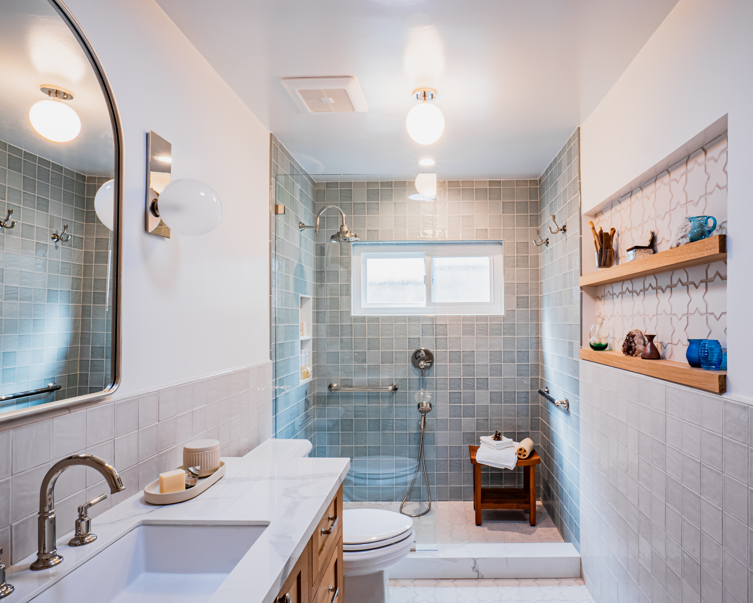 Bathroom with blue square tiles, walk-in shower, and built-in shelving.