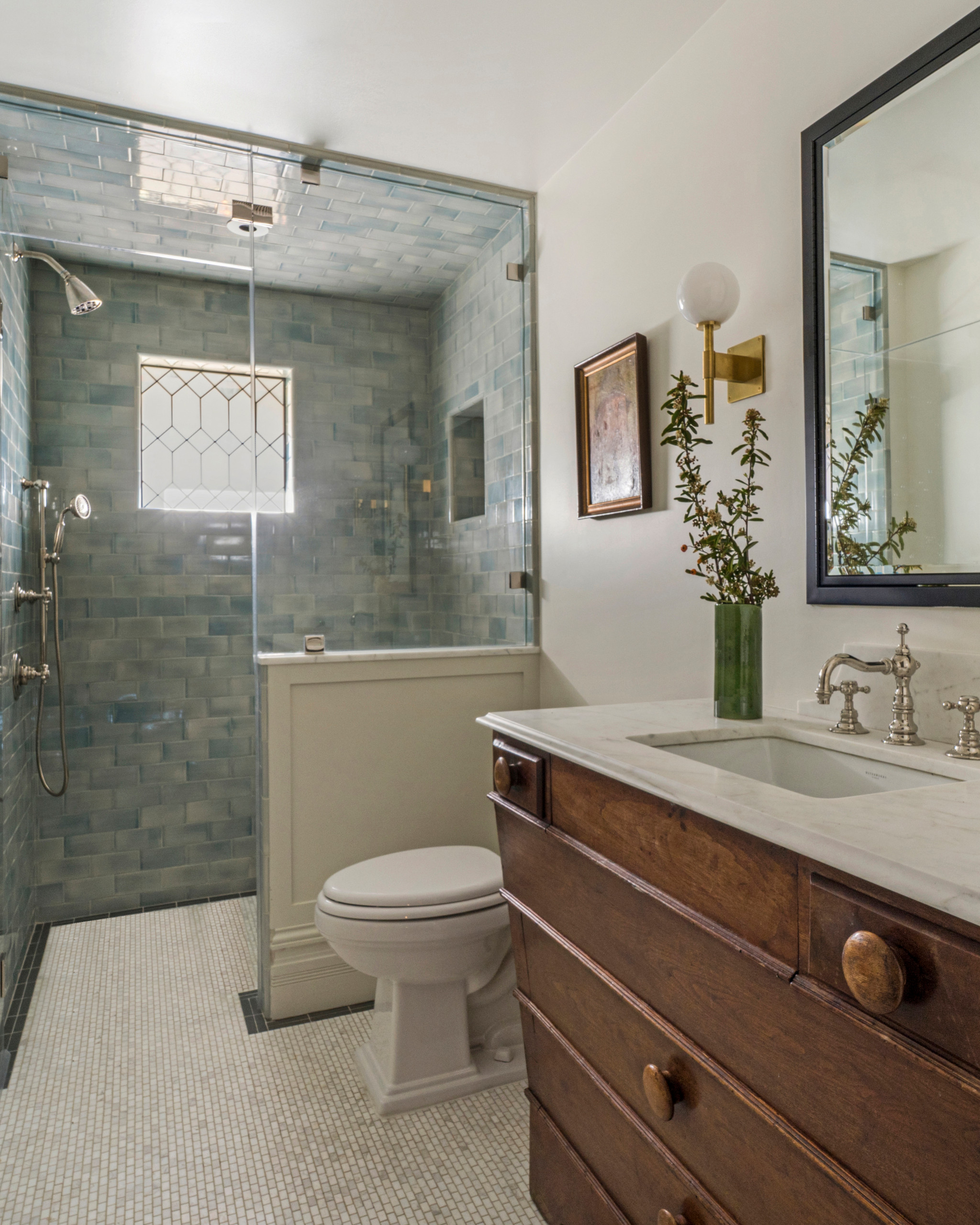 Vintage-style bathroom with wooden vanity and blue tiled shower.
