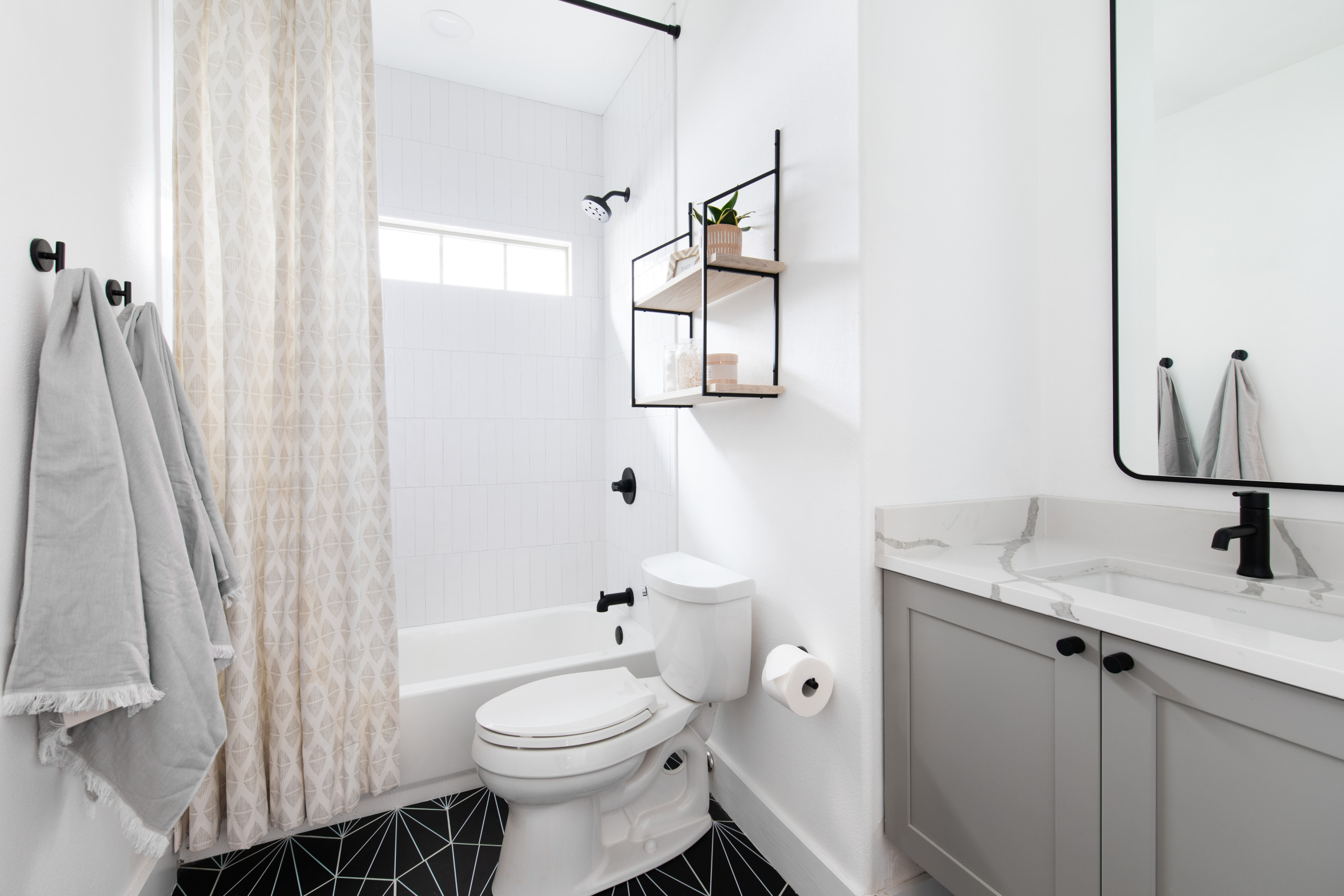 Minimalist small bathroom with geometric black floor tiles and modern fixtures.
