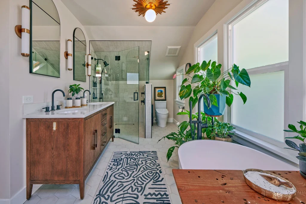Modern bathroom with wooden vanity, freestanding tub, indoor plants, and glass-enclosed shower
