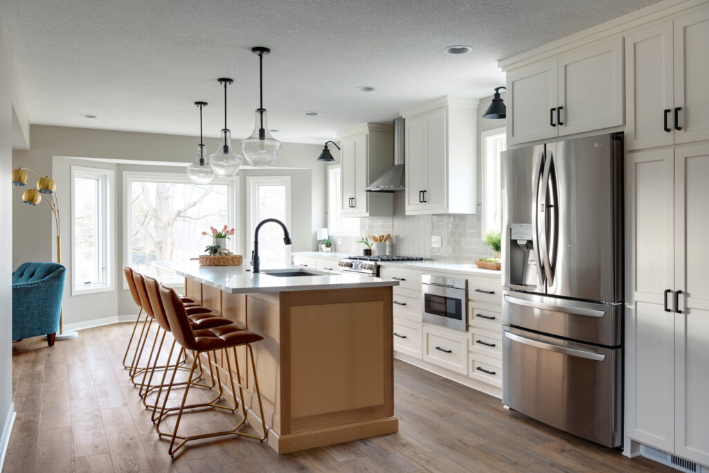 Bright kitchen with white cabinetry, light wood island, and modern pendant lighting.