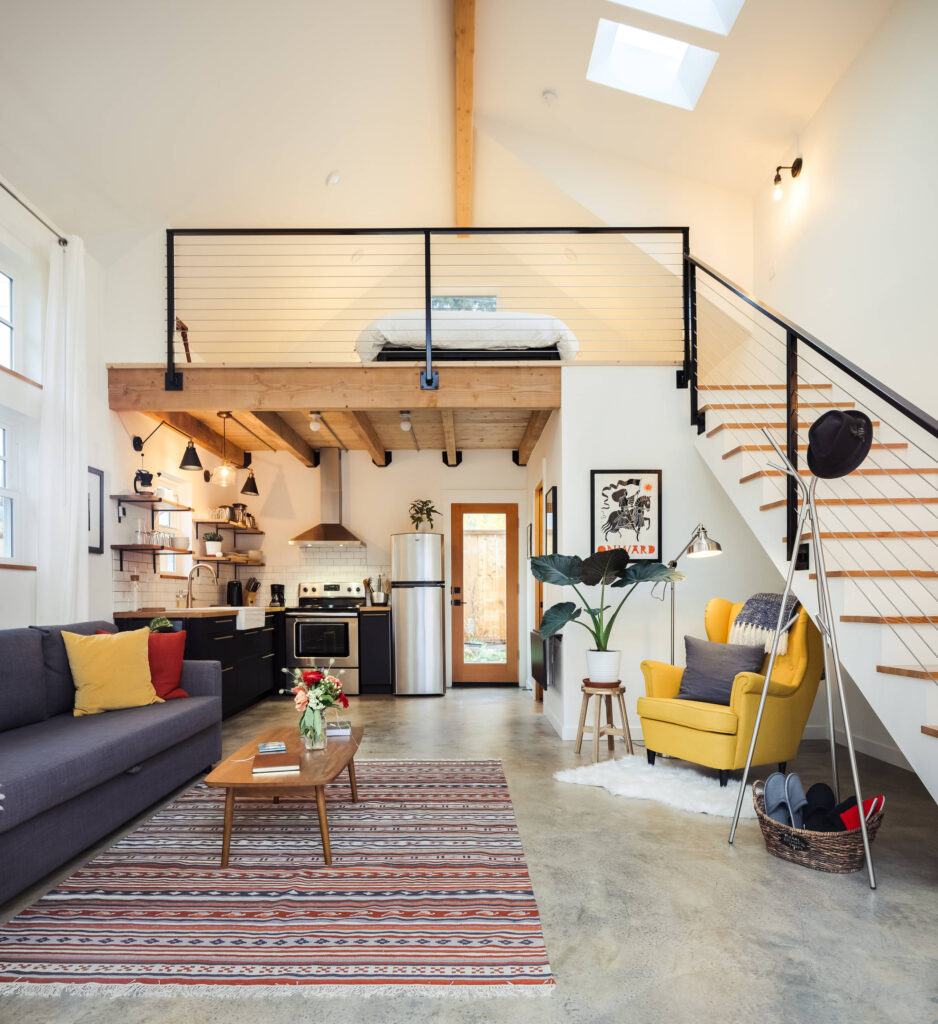 Modern open-concept loft with kitchen, living area, and upstairs sleeping space.