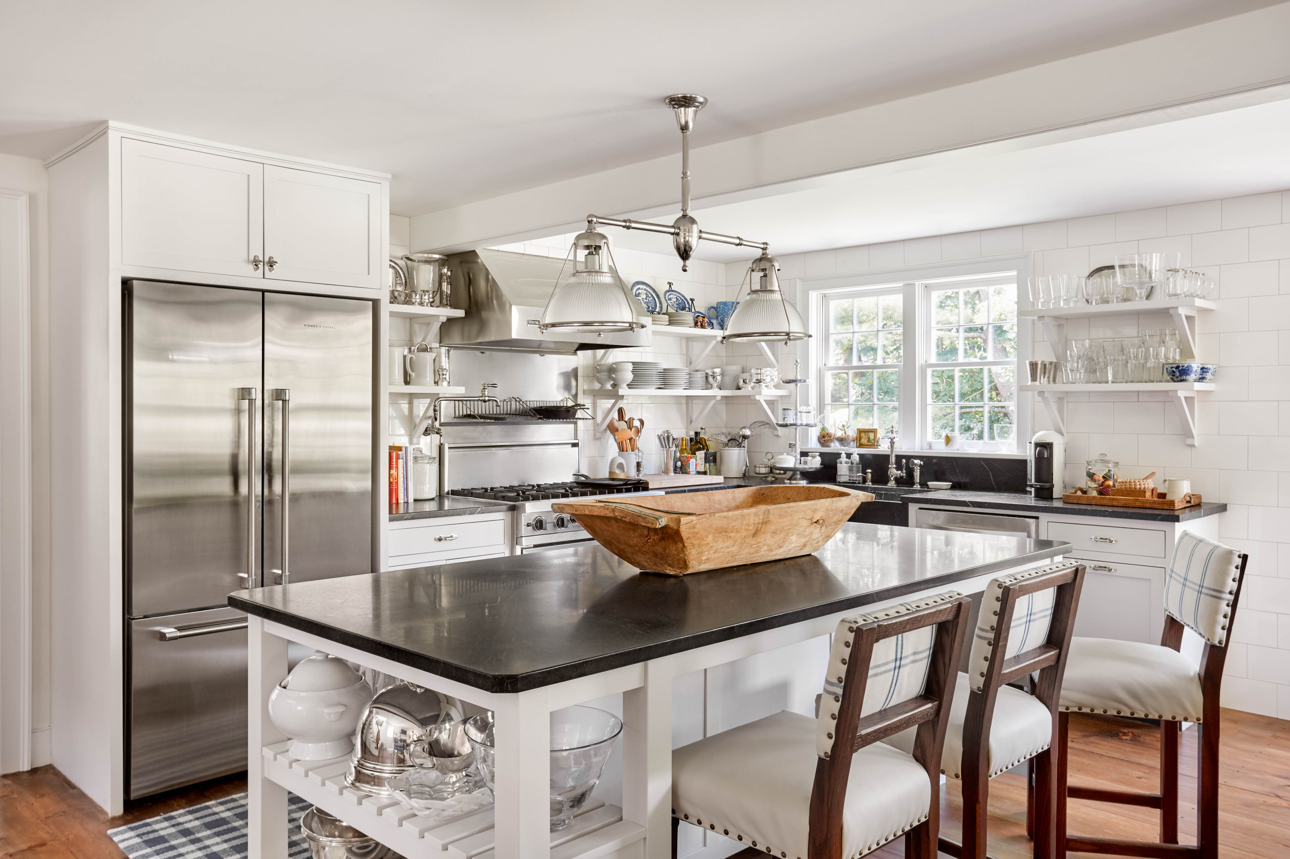 Bright kitchen with stainless steel appliances, black countertops, and white cabinetry.