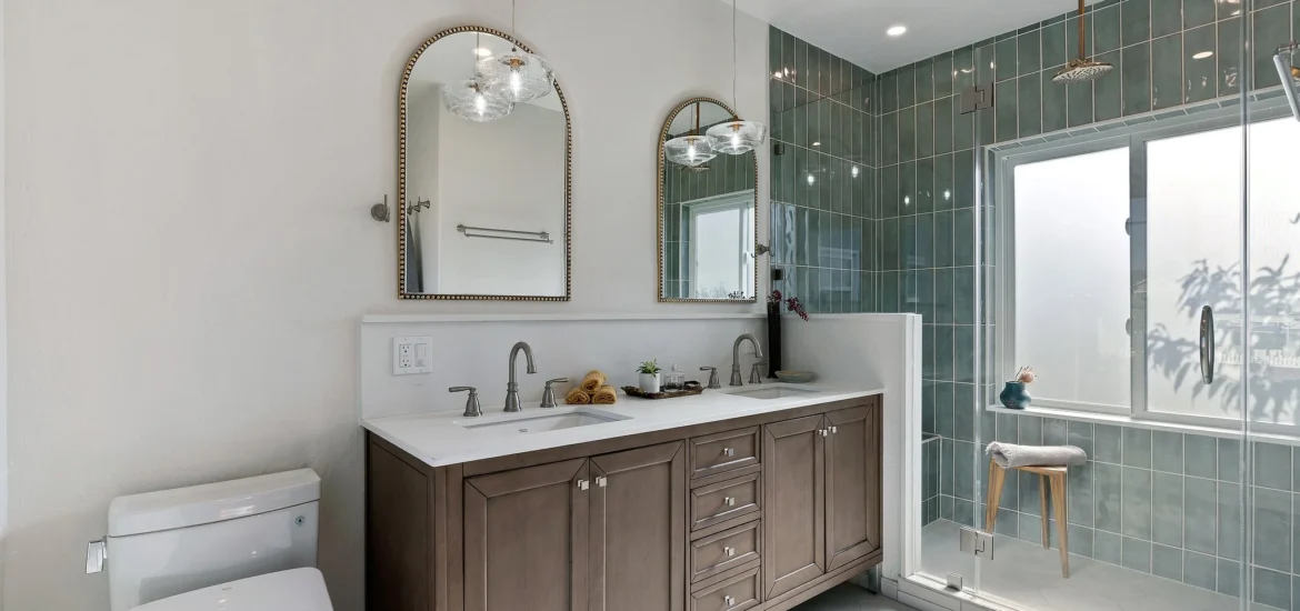 Elegant bathroom with double vanity, arched mirrors, and glass-enclosed shower.