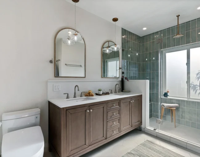 Elegant bathroom with double vanity, arched mirrors, and glass-enclosed shower.
