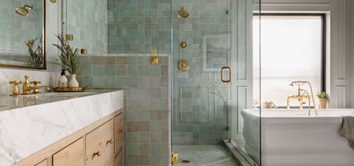 Luxurious bathroom with green square tile shower, marble vanity, and gold fixtures.