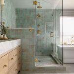 Luxurious bathroom with green square tile shower, marble vanity, and gold fixtures.